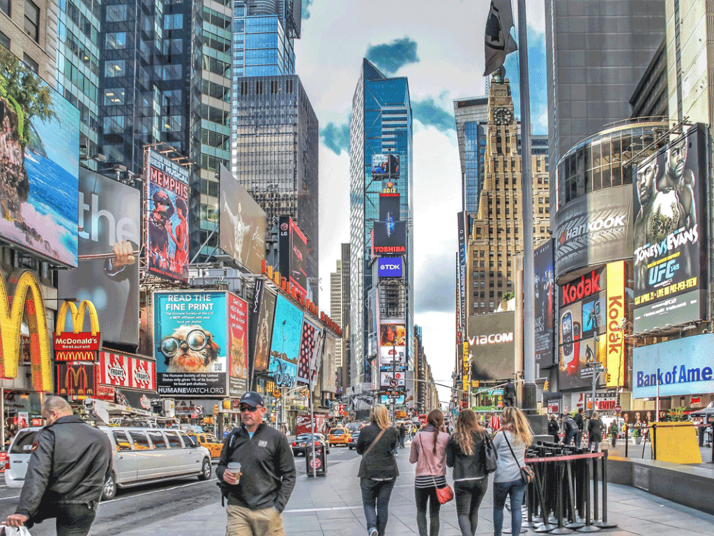 New York City with tall buildings, digital signs and people walking
